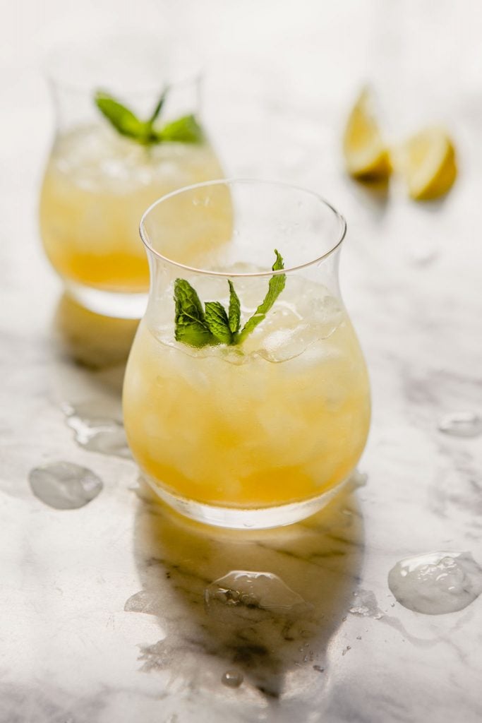 bourbon smash cocktail in a whiskey glass with crushed ice and a mint sprig.