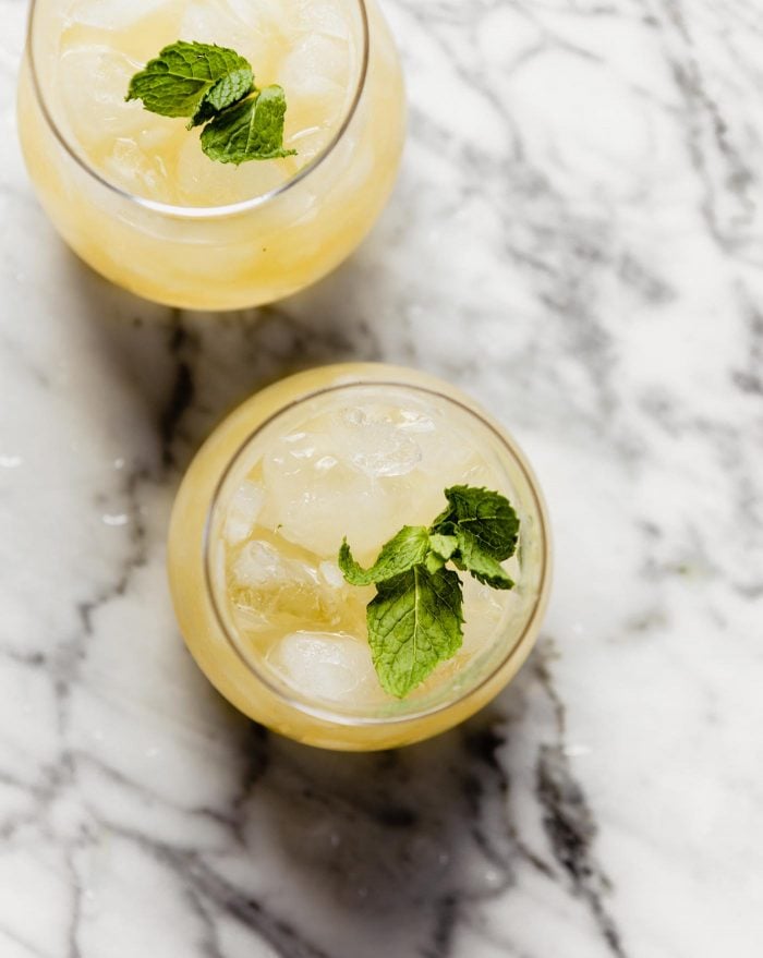 overhead image of two bourbon smash cocktails on a marble countertop