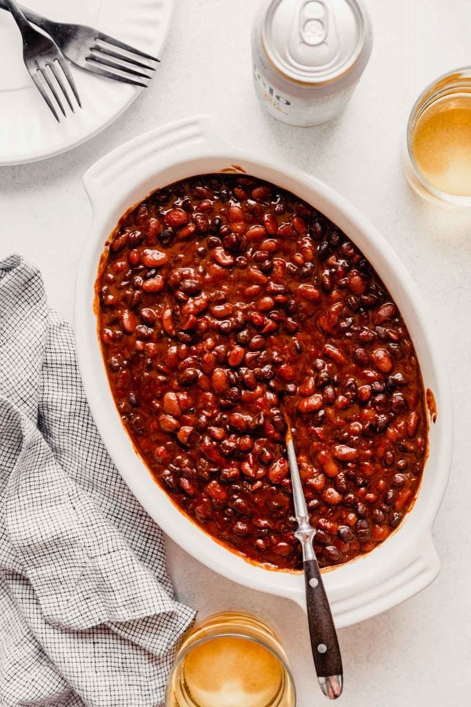 baked beans in a white oval dish with a spoon in them