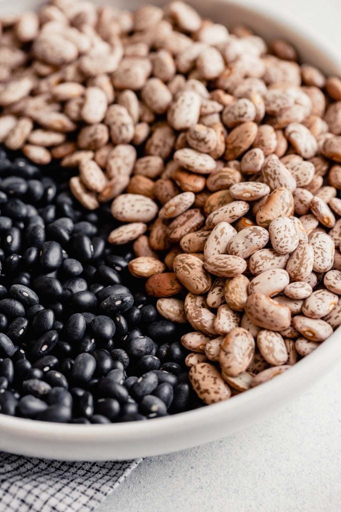 dry black beans and pinto beans in a white bowl