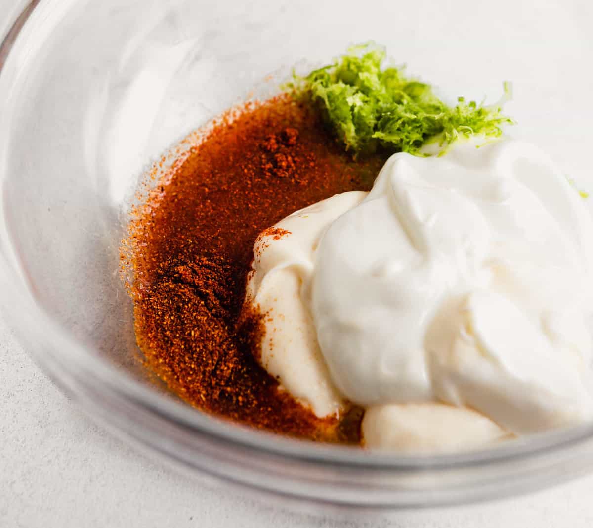 yogurt, lime zest and cayenne pepper in a glass bowl