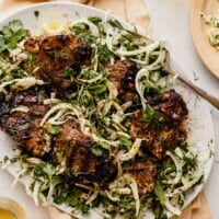 grilled lamb chops arranges over thinly sliced fennel on a white plate