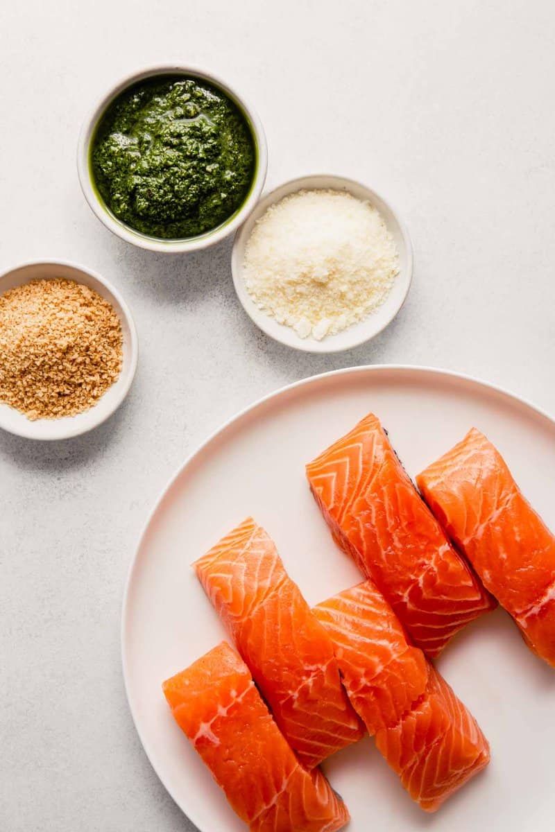image of salmon fillets on a plate with bowls of pesto, parmesan and bread crumbs set around it