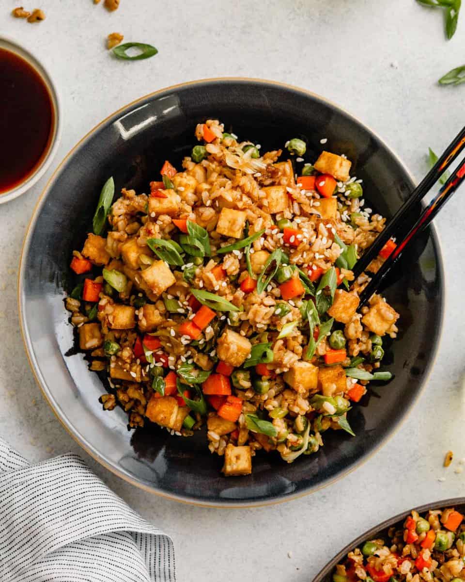 Overhead image of fried rice in a skillet on a table with a wooden spoon set in it