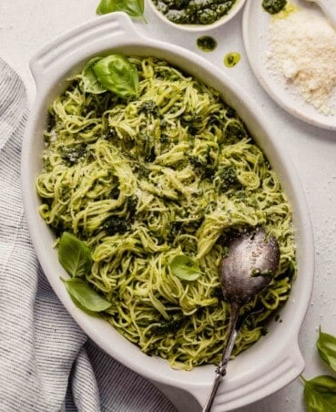 pesto noodles in a white oval dish with cheese and pesto set around