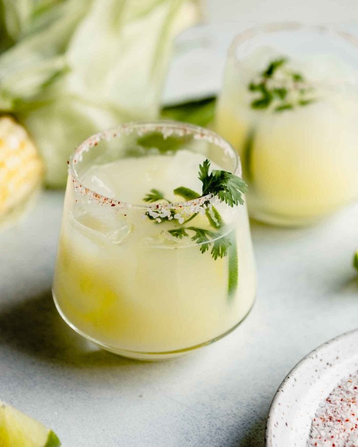 cocktail glass filled with a creamy yellow cocktail and garnished with cilantro.