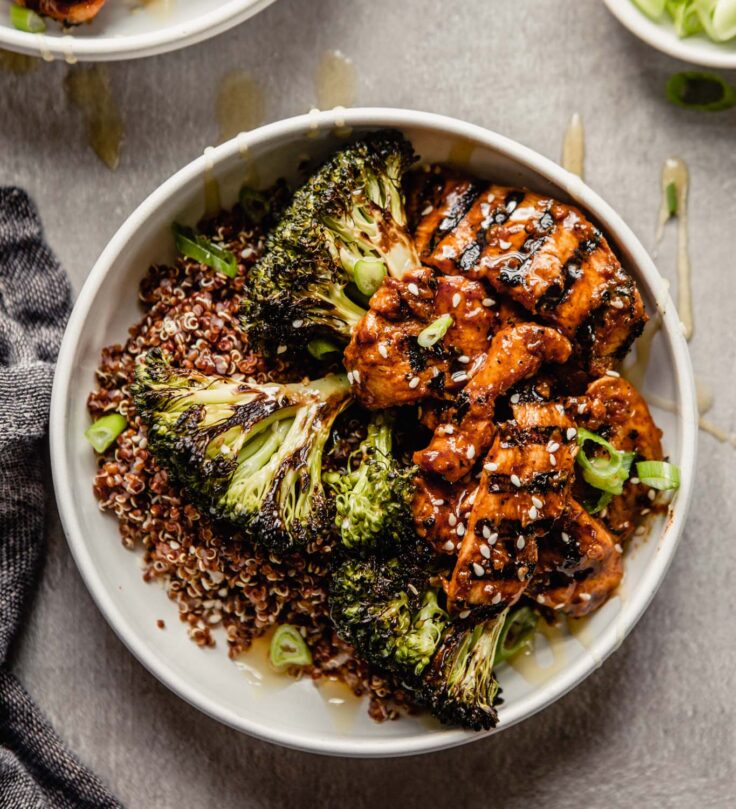 white bowls filled with quinoa and topped with roasted broccoli and charred meat