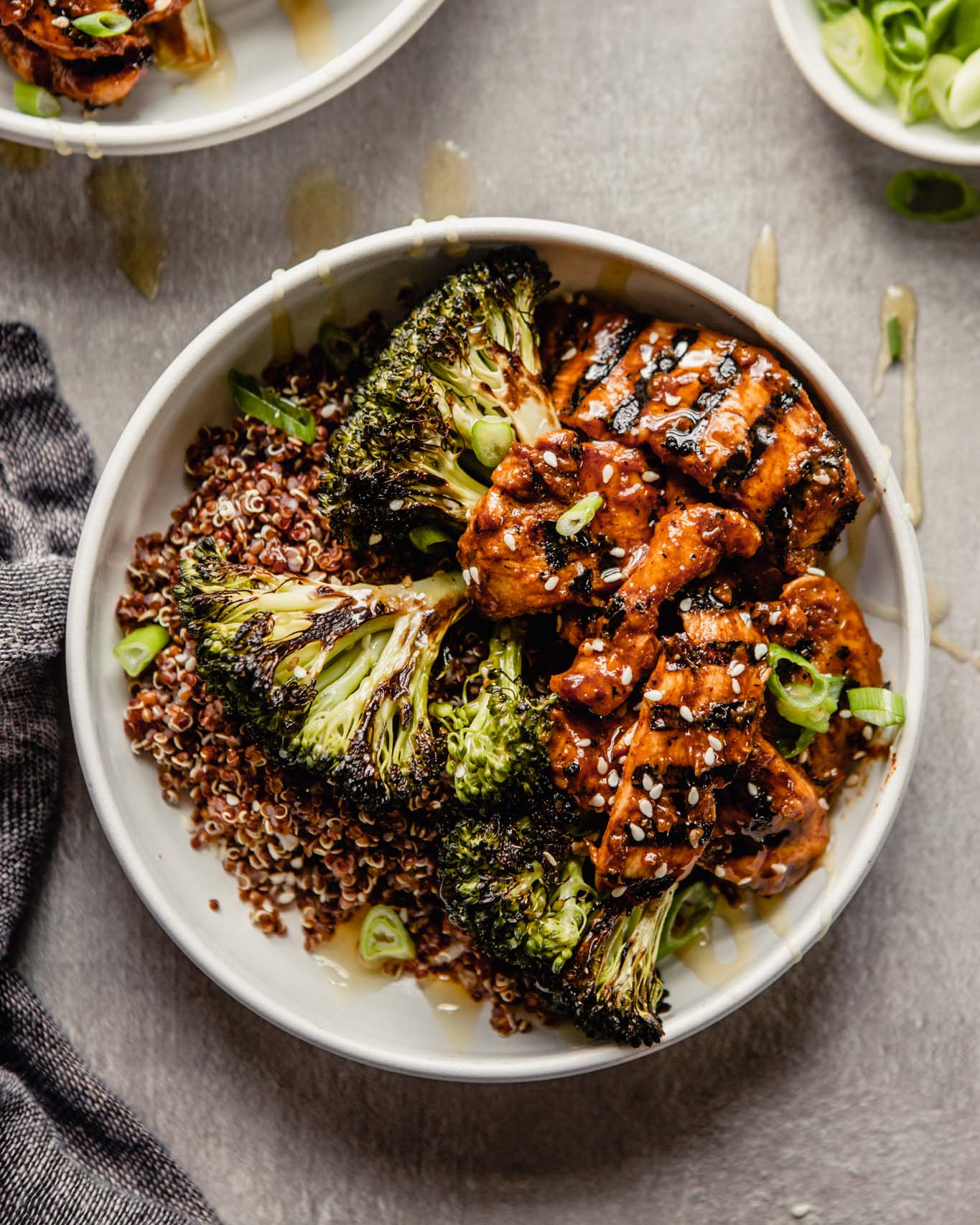 white bowls filled with quinoa and topped with roasted broccoli and charred meat
