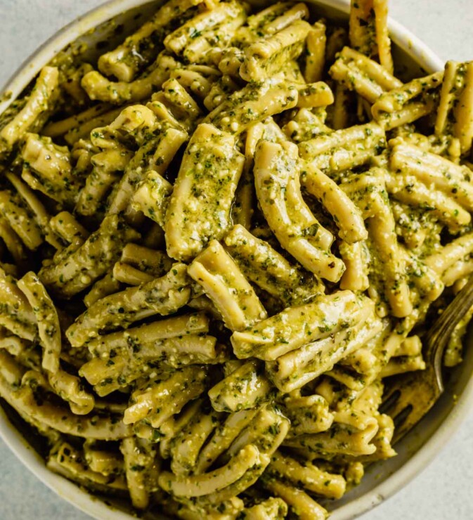 a white bowl filled with pesto-coated pasta.