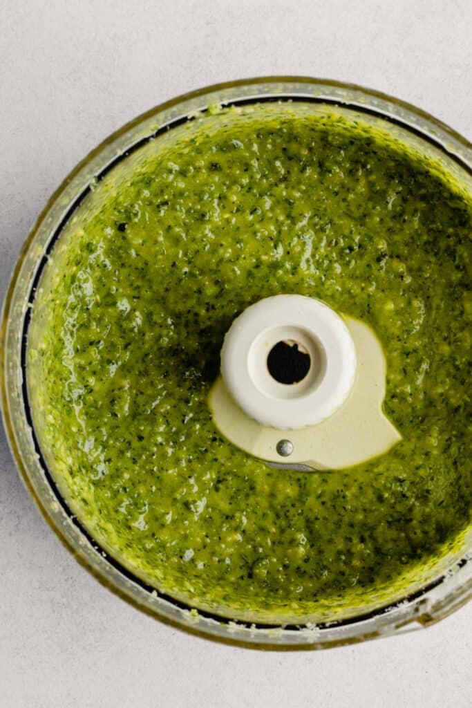 food processor bowl filled with bright green pesto sauce