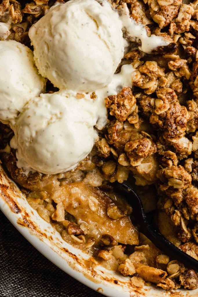 close up of apple crisp with melted ice cream dripping over it 