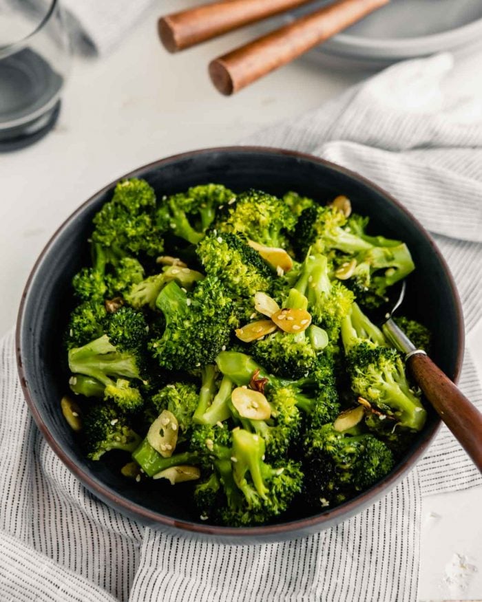 sauteed broccoli in a white bowl with a wooden spoon