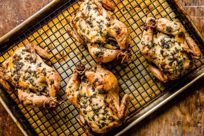 herb-roasted cornish hens on a wire rack set inside a baking sheet