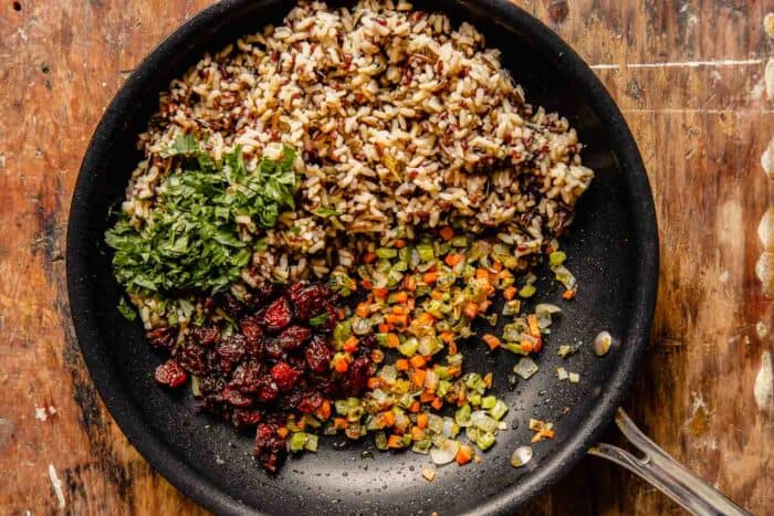 mixed rice, carrots, celery, dried cranberries and fresh herbs in a nonstick skillet