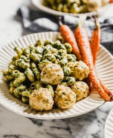 chicken meatballs on a plate with pesto pasta and roasted carrots
