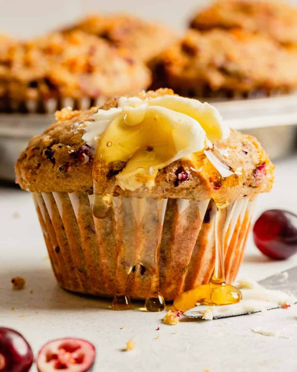 cranberry muffin topped with butter and drizzled with honey