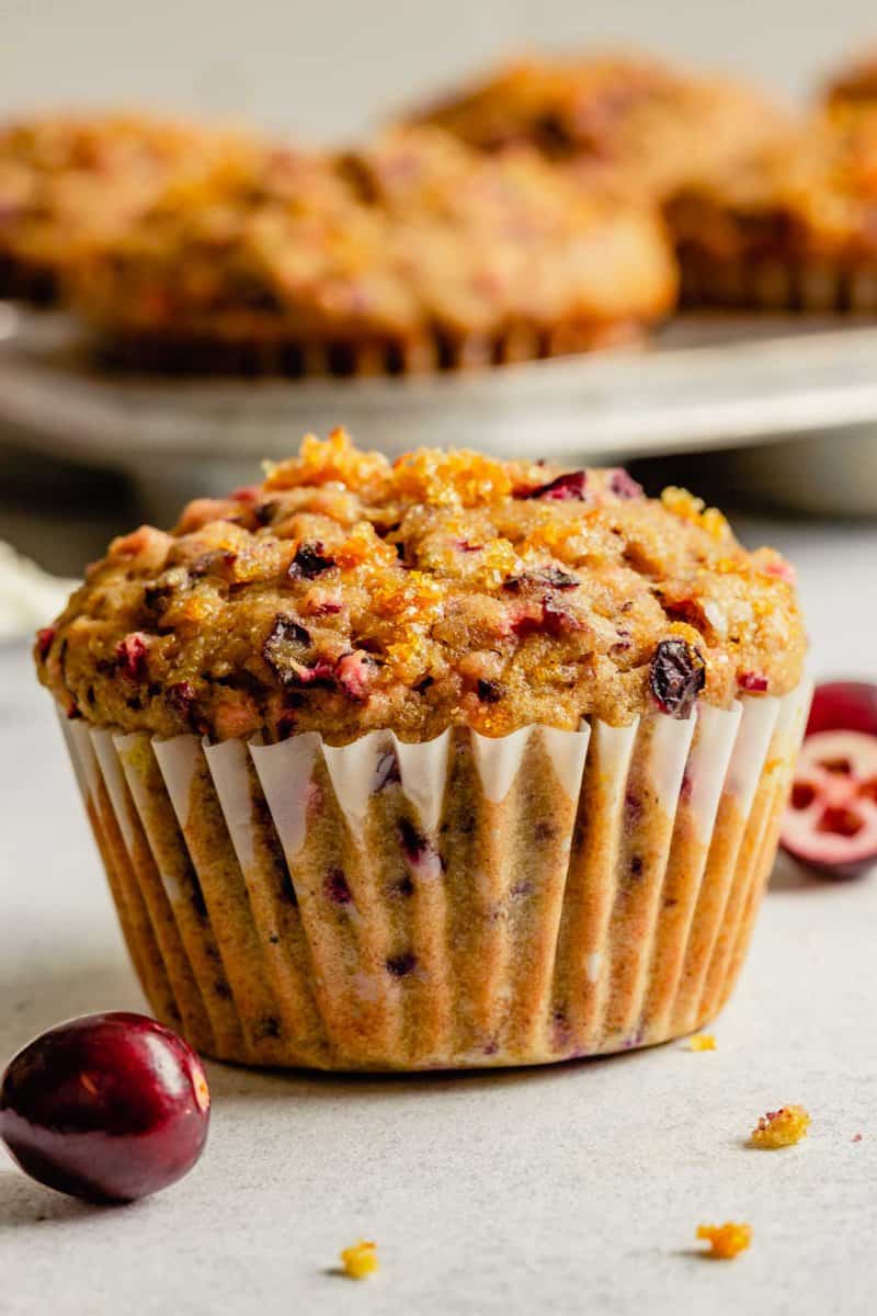 cranberry orange muffin set on a table with more muffins in the background in a muffin tin