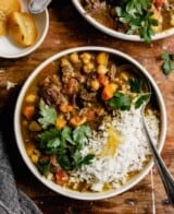 lamb stew with chickpeas, parsley, and rice in a white bowl set on a wooden table
