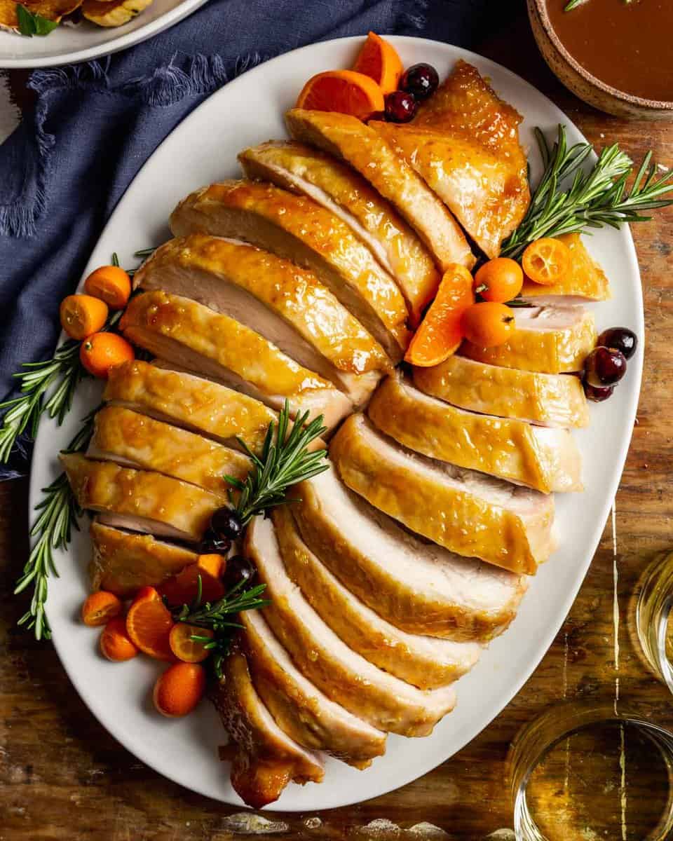 sliced turkey breast on a large white oval set on a wooden table
