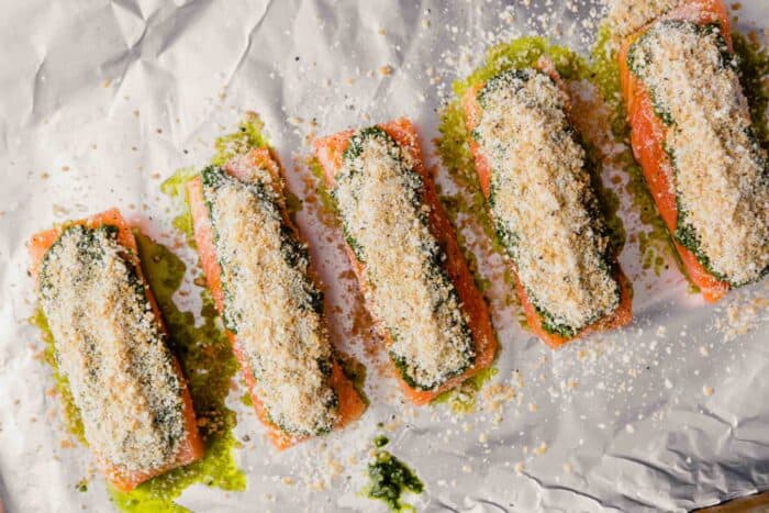 salmon fillets on foil topped with pesto and breadcrumbs
