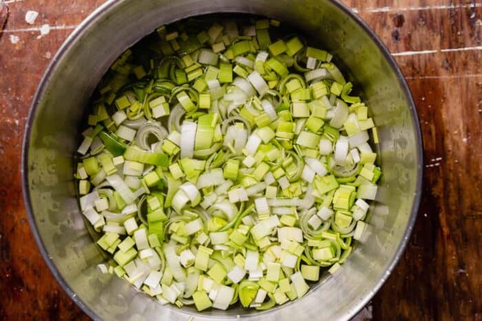chopped leeks in a large metal bowl filled with water