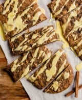 cookie bars with orange glaze arranges on a piece of parchment paper on a wood table