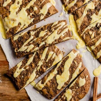 cookie bars with orange glaze arranges on a piece of parchment paper on a wood table