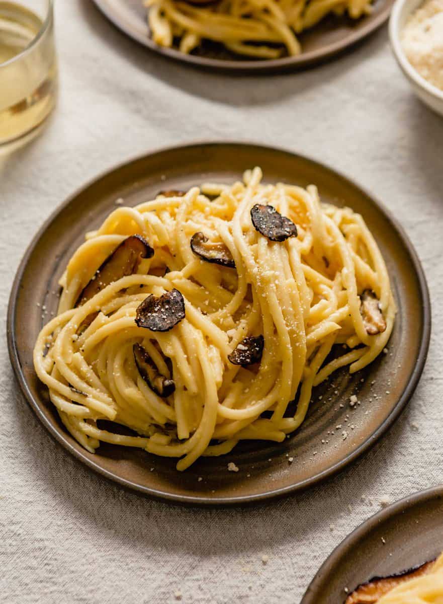 brown plates topped with creamy pasta with mushrooms and truffle shavings