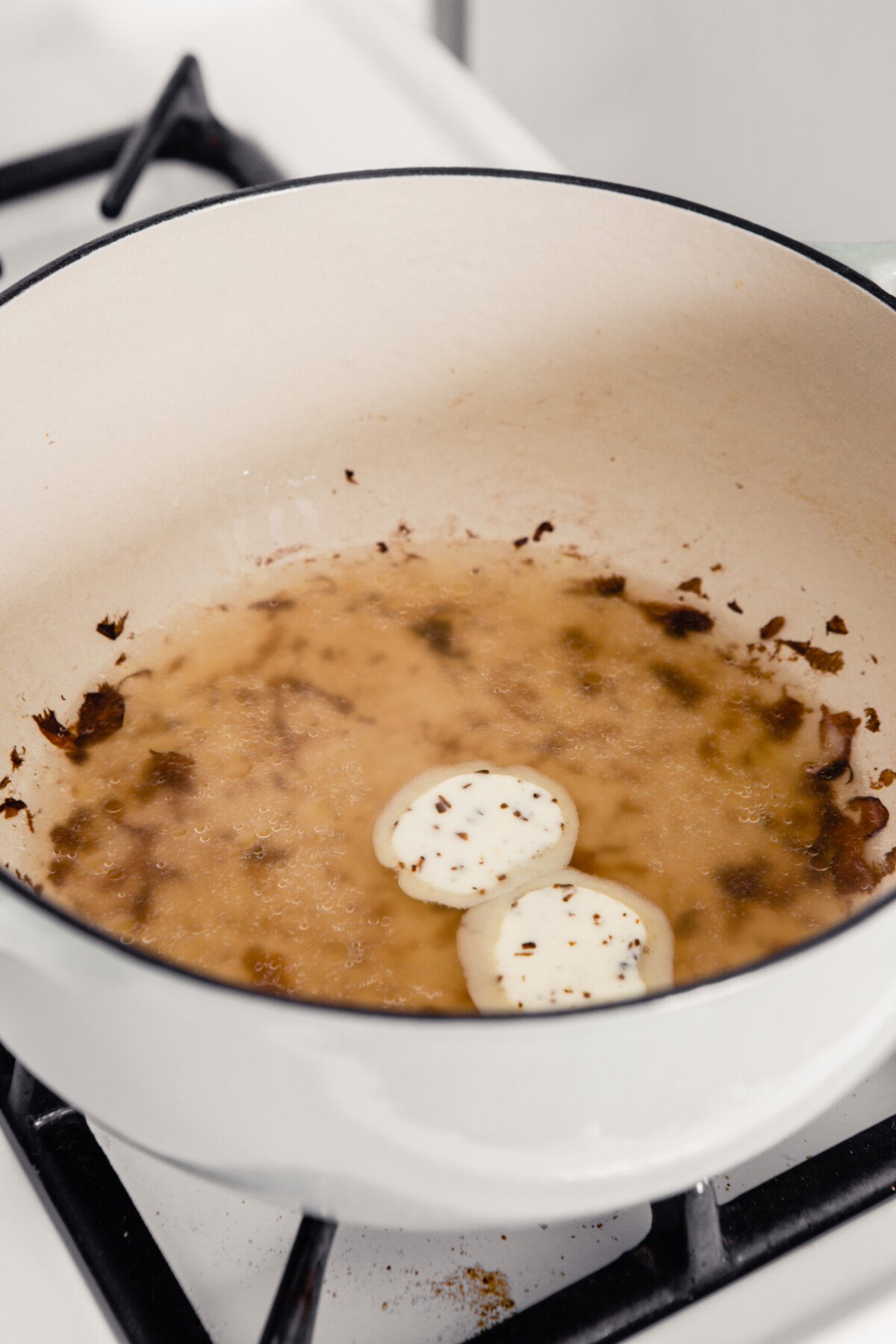 Truffle butter melting into water in a large Dutch oven. 