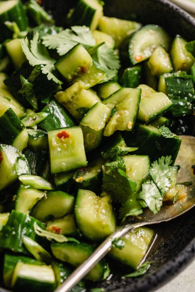 close up of crushed cucumber chunks with red pepper flakes and dressing