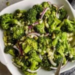 broccoli salad with pepitas, red onion and crumbled cheese in a square white bowl