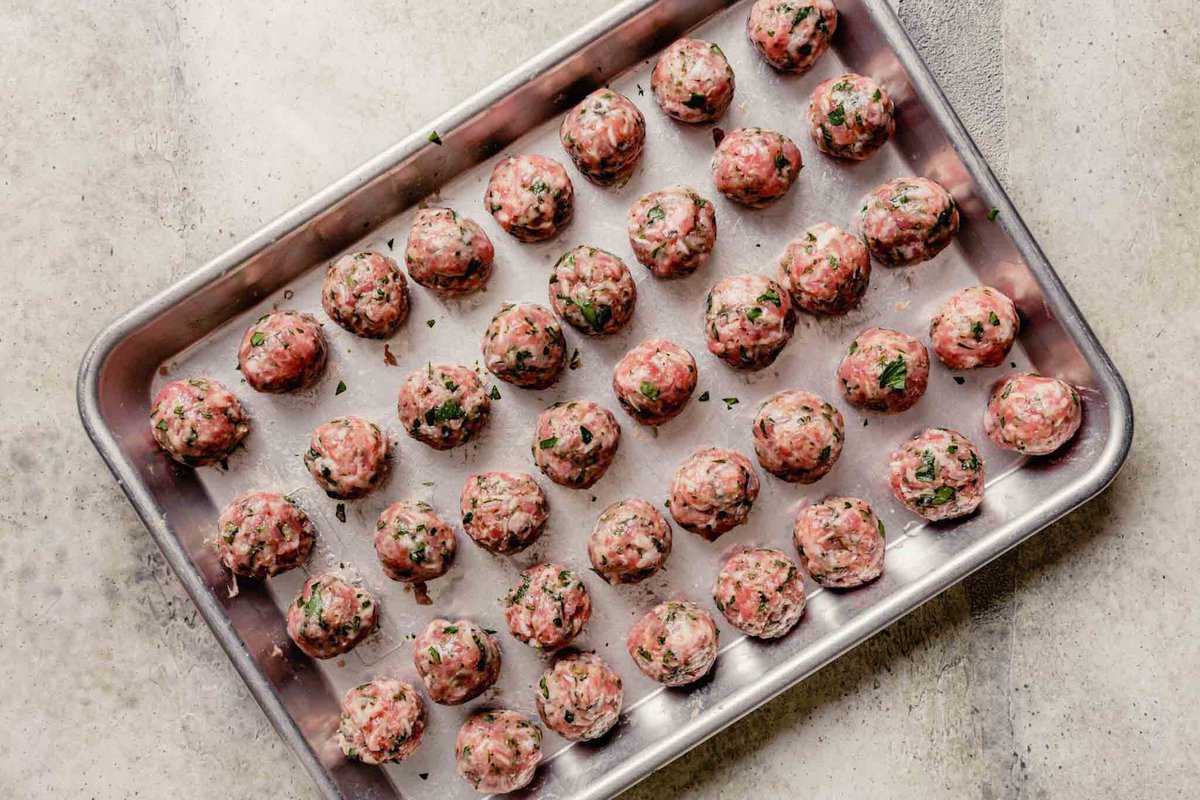 raw meatballs arranged on a baking sheet