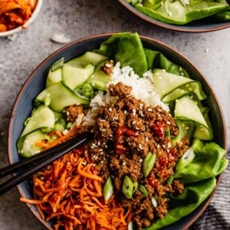 blue bowls filled with ground beef over rice, carrots and cucumbers