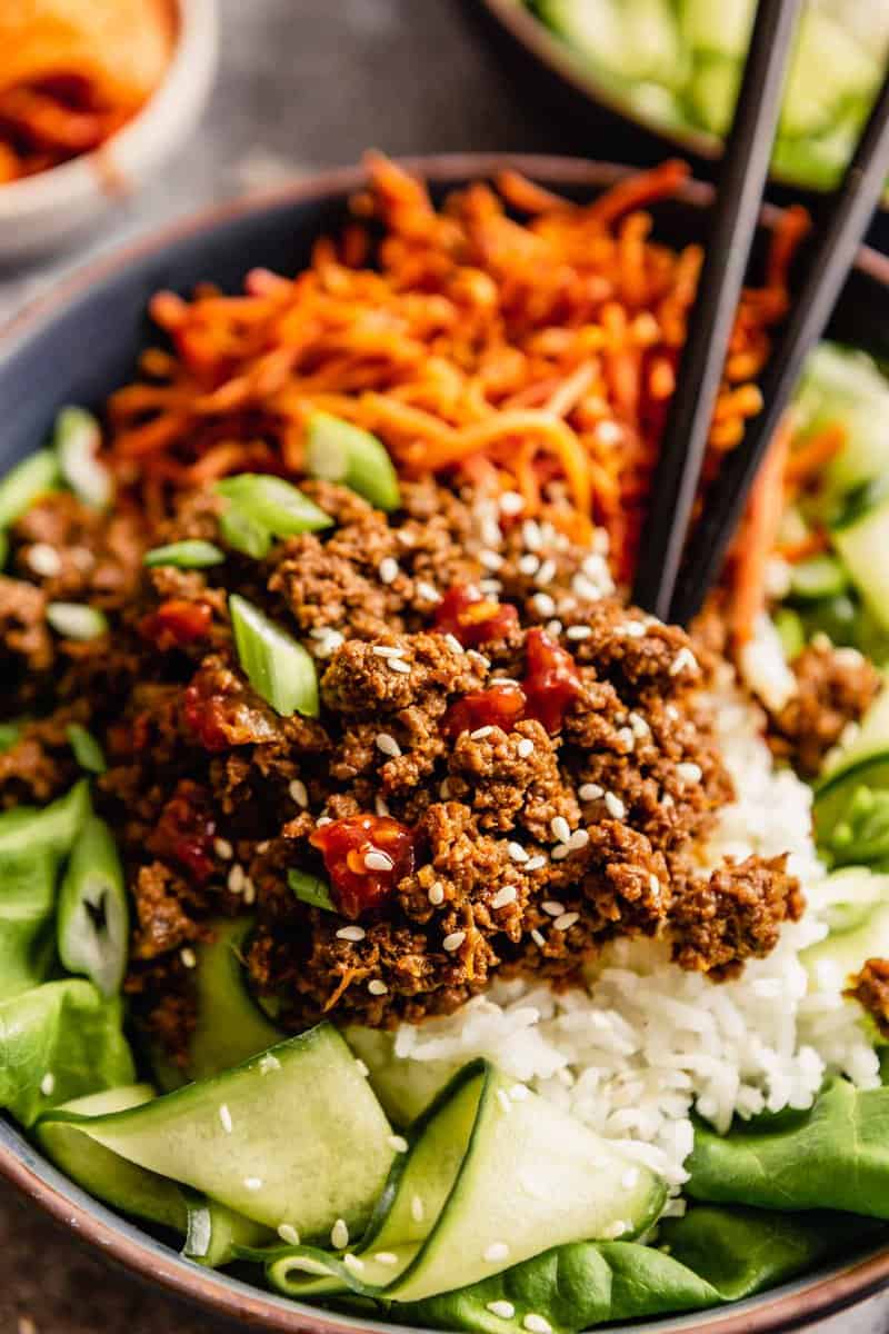 blue bowls filled with ground beef over rice, carrots and cucumbers