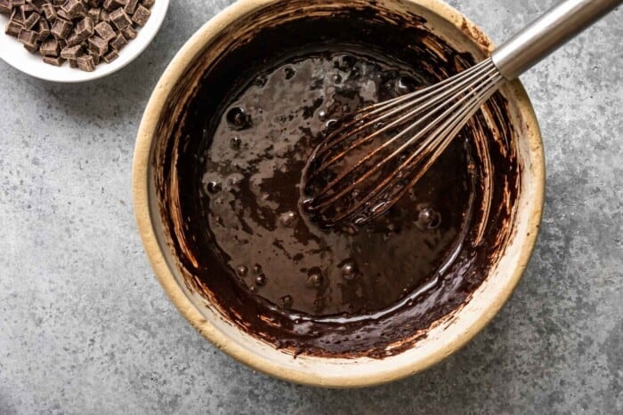 glossy chocolate mixture in a mixing bowl with a whisk