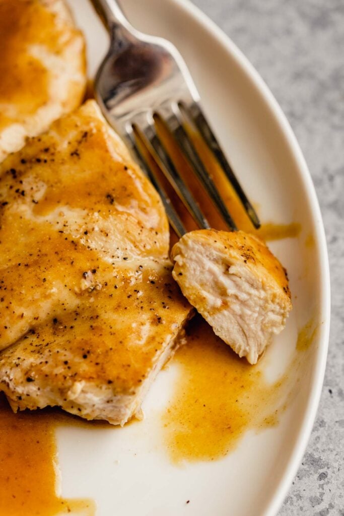 pan seared chicken on a white plate with a bite cut out and on a fork