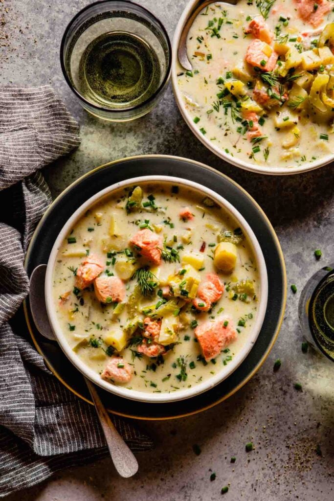 white bowl filled with a creamy white soup featuring chunks of salmon.