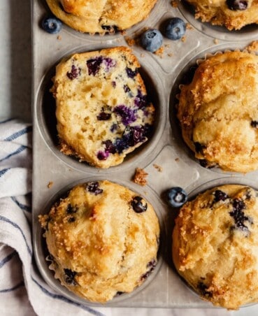 muffins in a silver muffin tin with one muffin cut in half, cut side up