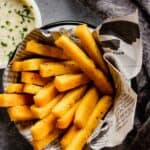 polenta fries piled in a metal bowl with a newspaper