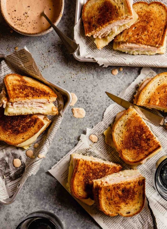 grilled sandwiches on newspaper set in metal trays with drips of sauce scattered around