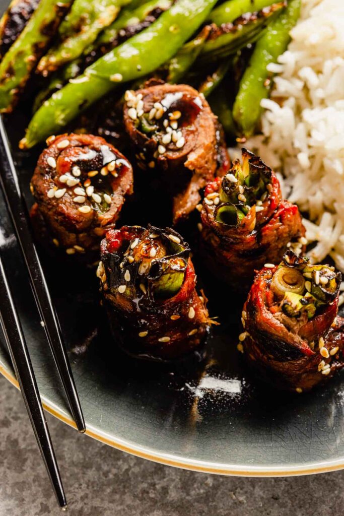 beef scallion rolls on a plate with charred snap peas and white rice