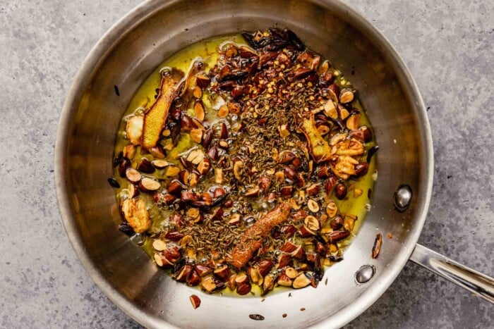 Toasted lemon peel, sliced scallion whites, smashed garlic, chopped almonds and cumin seeds in a skillet with olive oil.