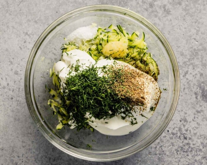 yogurt, herbs and zucchini in a glass mixing bowl