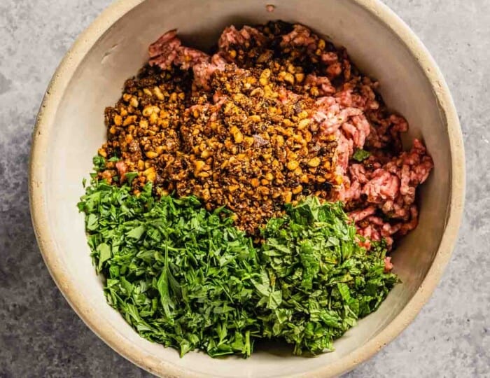 ground lamb mixed with spices, herbs and nuts in a bowl