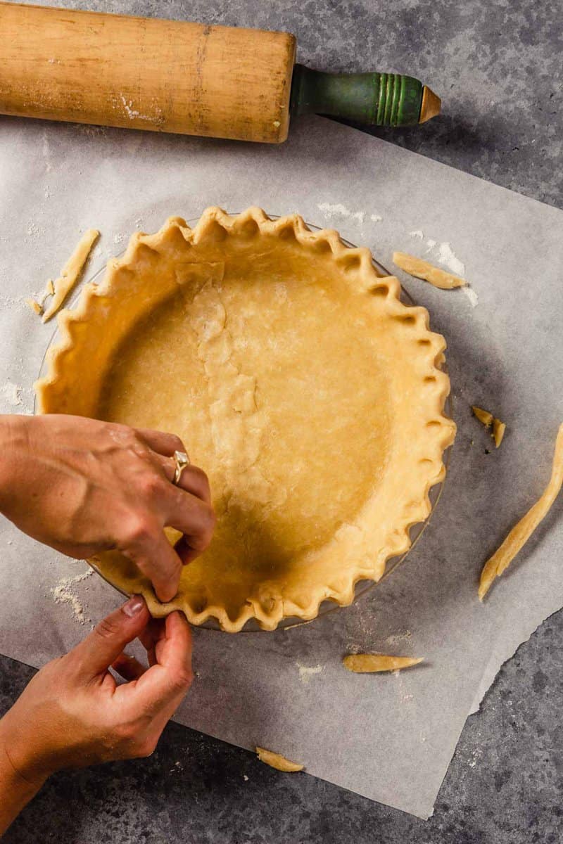 someone crimping the edges of pie dough in a pie plate as a makeahead dish