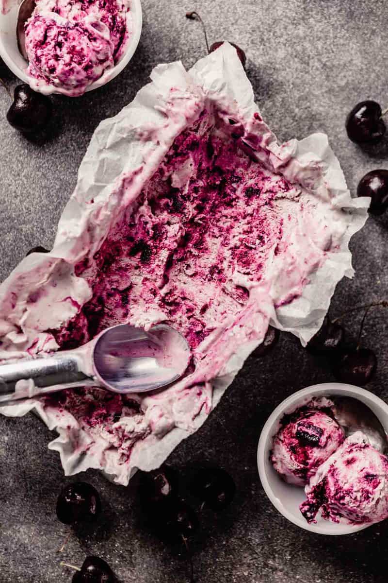 swirled cherry ice cream in a loaf pan with scoops taken out and placed in small white bowls