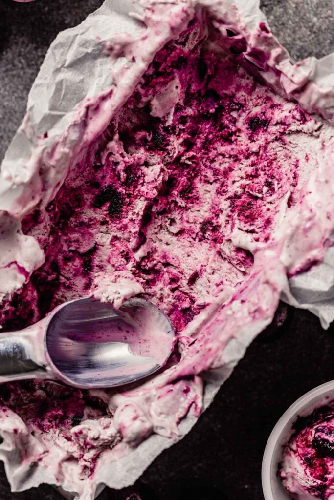 swirled cherry ice cream in a loaf pan with scoops taken out and placed in small white bowls