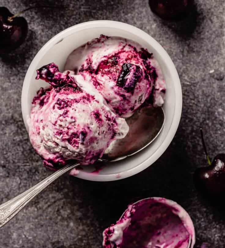 small white bowl with two scoops of cherry ice cream