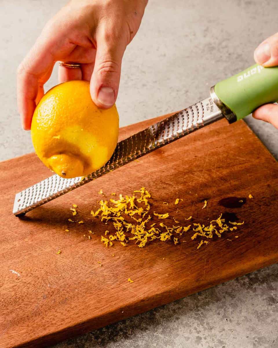 two hands zesting a lemon using a microplane