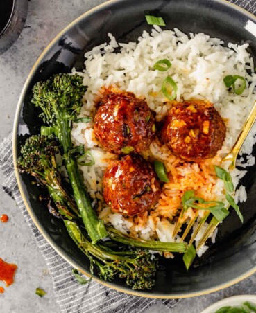 glazed meatballs on a plate of white rice with charred broccolini on the side
